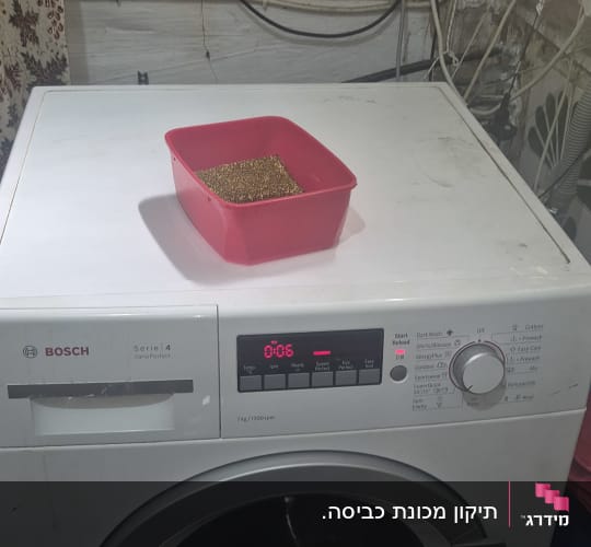 מכונת כביסה עם קערה אדומה על גבי המכסה